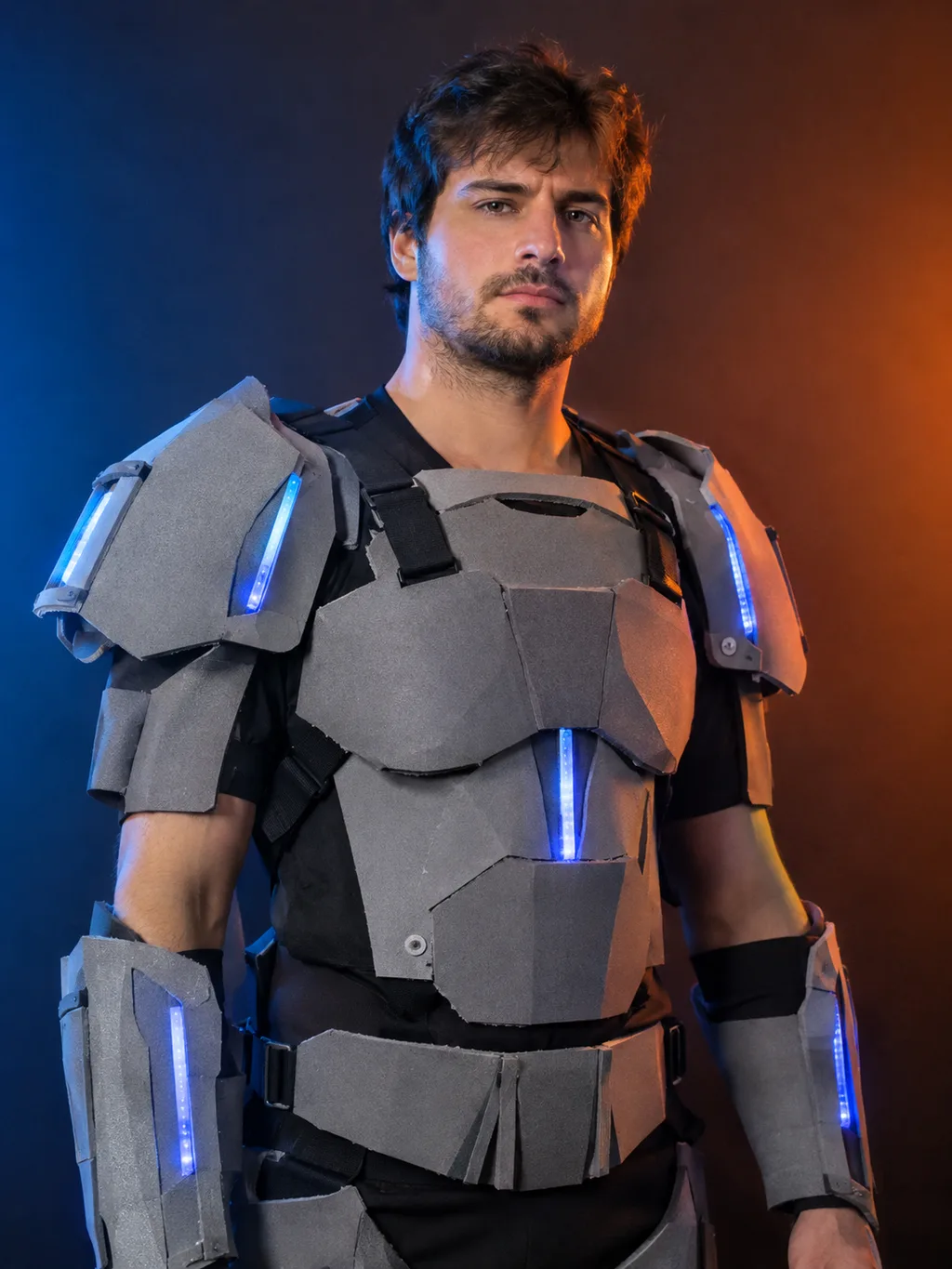 Adult model wearing a handmade robot costume with matte foam armor panels and blue LED accents under studio lighting